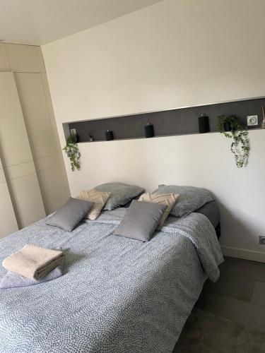 ein Schlafzimmer mit einem Bett mit Kissen darauf in der Unterkunft Le Saint-Brice de Paris in Saint-Brice-sous-Forêt