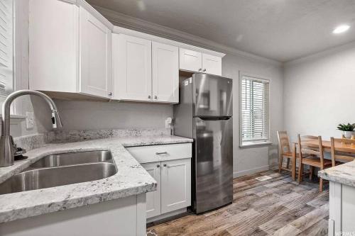 a kitchen with white cabinets and a stainless steel refrigerator at Entire Tiny House with Large Yard Fenced In! in West Valley City