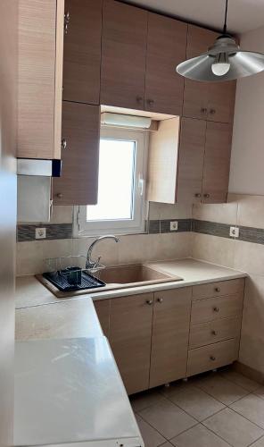 a kitchen with wooden cabinets and a sink and a window at Casa by Hokkum Studios in Kokkari