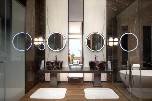 a bathroom with two sinks and a tub and mirrors at Jumeirah Guangzhou-Complimentary Shuttle Bus to Canton Fair Complex during Canton Fair Period in Guangzhou