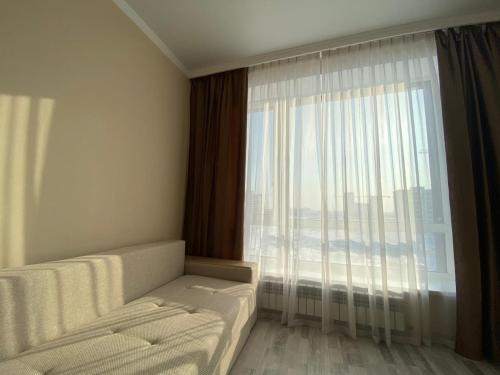 a room with a large window with a couch and a bed at Sati Club House in Prigorodnyy
