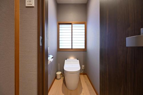 a small bathroom with a toilet with a window at Kyoto Fushimi Sutekichi Private Hotel in Fushimi