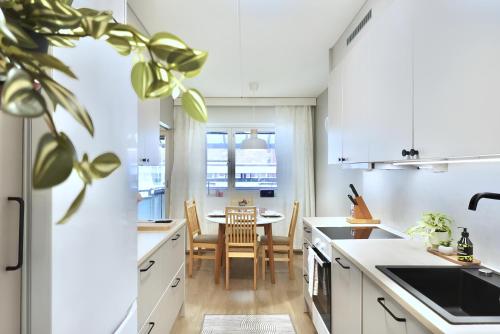 a kitchen with white cabinets and a dining table at Spacious Haven near Mall and Convention Center in Helsinki