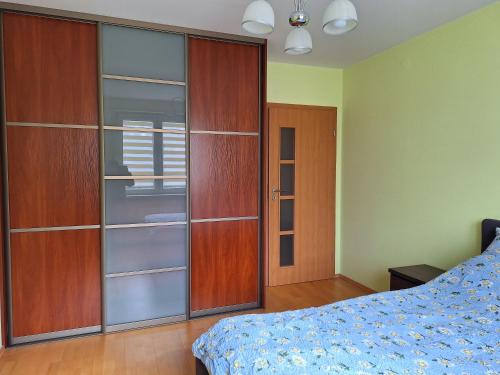 a bedroom with a bed and a wooden closet at Apartament Rose Stalowa Wola in Stalowa Wola