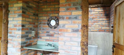 a bathroom with a sink and a brick wall at Cabaña Lato_puzhio in Chordeleg