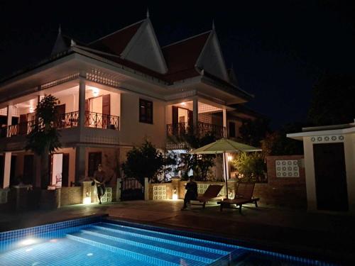 a house with a swimming pool at night at La maison bleue BTB in Phumĭ Kâmpóng Âmpĭl