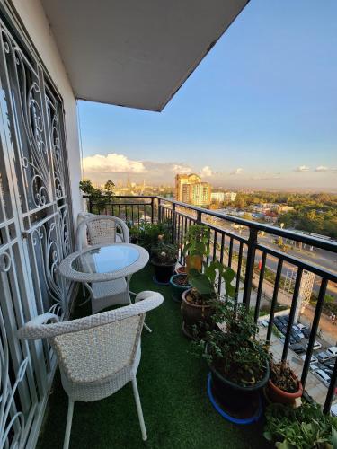 uma varanda com cadeiras e mesas e vasos de plantas em Vesta Garden Apartment em Nairobi