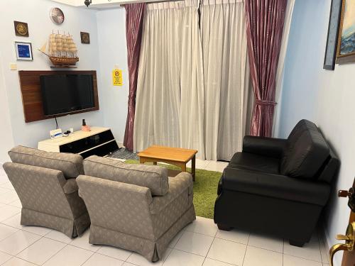 a living room with two chairs and a flat screen tv at Sevenseas Marina Crescent in Port Dickson