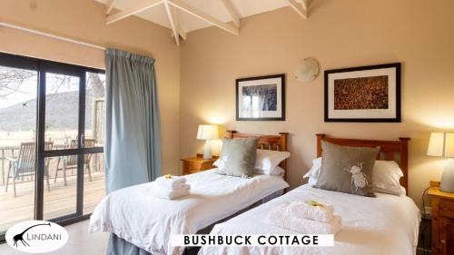 two beds in a bedroom with a balcony at Lindani Game and Lodges in Vaalwater