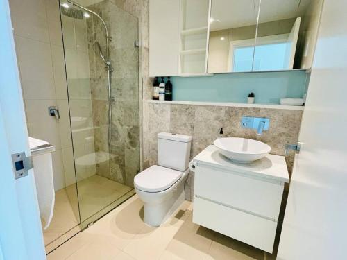 y baño con aseo, lavabo y ducha. en Fascinating waterview 2 bedrooms condo (Parking), en Sídney