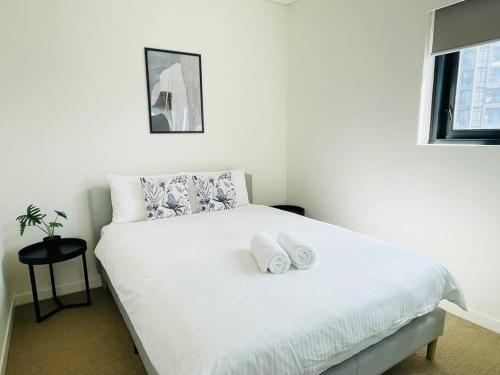 1 dormitorio con 1 cama blanca y 2 toallas en Fascinating waterview 2 bedrooms condo (Parking), en Sídney
