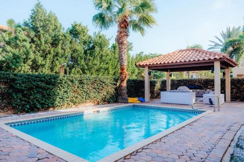 a swimming pool with a gazebo and a palm tree at Gold coast elegance with private pool in Noord