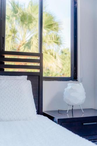 a bedroom with a bed and a window with a palm tree at Gold coast elegance with private pool in Noord