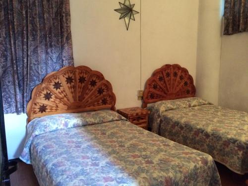 a hotel room with two beds and a window at Hotel Estelar in Taxco de Alarcón