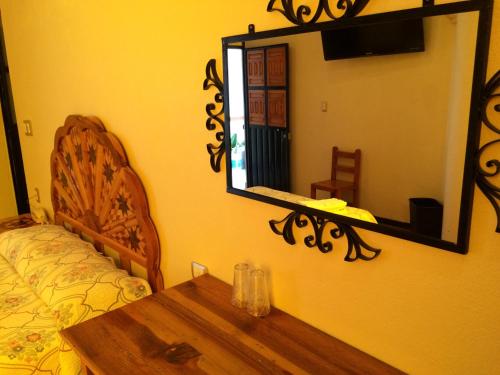a bedroom with a mirror and a bed and a wooden table at Hotel Estelar in Taxco de Alarcón