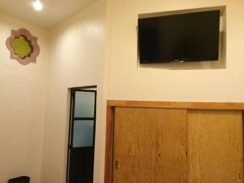 a room with a television on the wall and a door at Hotel Estelar in Taxco de Alarcón