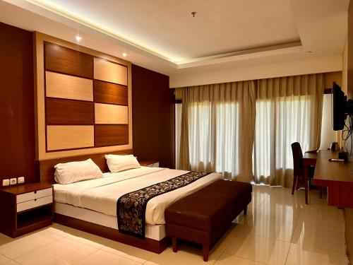 a hotel room with a bed and a desk and a desk at GRAND MULYA HOTEL BOGOR in Sukaraja