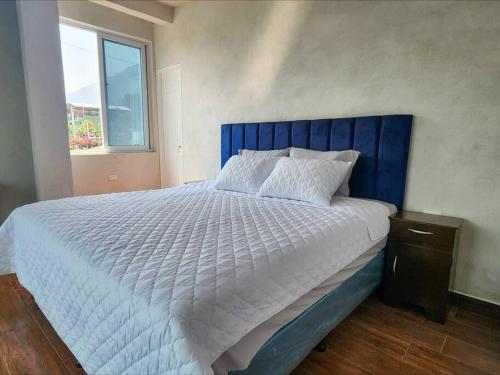 een groot bed met een blauw hoofdeinde in een slaapkamer bij Habitación#1 Casa Rosita a metros del Lago in San Pedro La Laguna