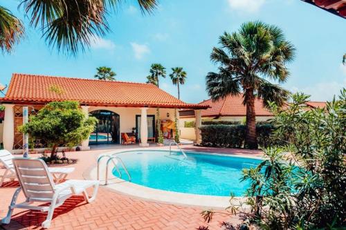 a house with a swimming pool and palm trees at The elegance of Tierra del Sol with private pool in Palm-Eagle Beach