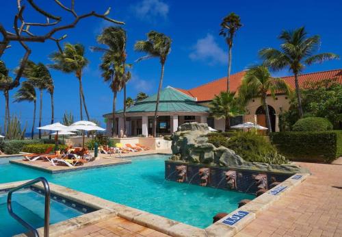 a pool at a resort with palm trees at Comfortable house in tierra del sol resort & golf in Palm-Eagle Beach