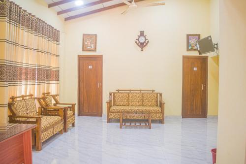 uma sala de estar com dois sofás e um relógio na parede em Yashora Gimanhala em Anuradhapura
