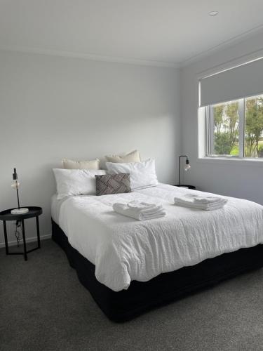 a white bedroom with a large white bed with a window at Modern and new house in Taupiri