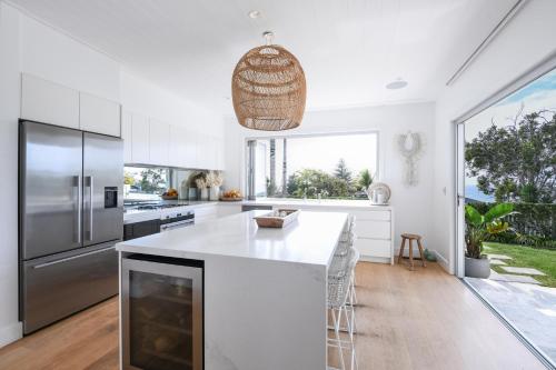 una cocina con armarios blancos y una gran isla en Hamptons style Warriewood Beachhouse en Mona Vale