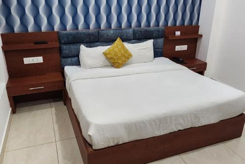 a bedroom with a bed with a blue padded headboard at Hotel Ganga Amrit Haridwar Near Railway Station in Haridwār