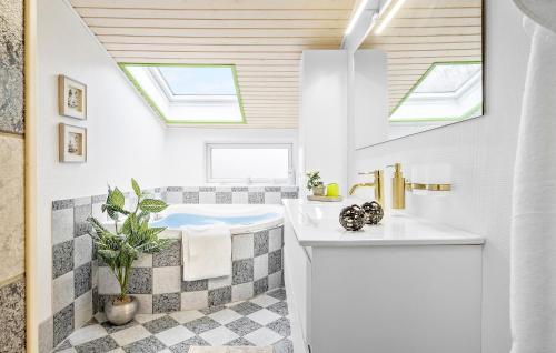 La salle de bains est pourvue d'une baignoire, d'un lavabo et de lucarnes. dans l'établissement Stunning Home In Hals With Sauna, à Hals