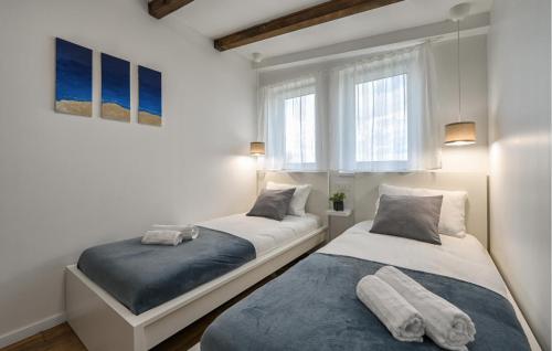 2 Betten in einem Zimmer mit weißen Wänden und Fenstern in der Unterkunft Cozy Home In Gornji Kneginec With Kitchen in Gornji Kneginec