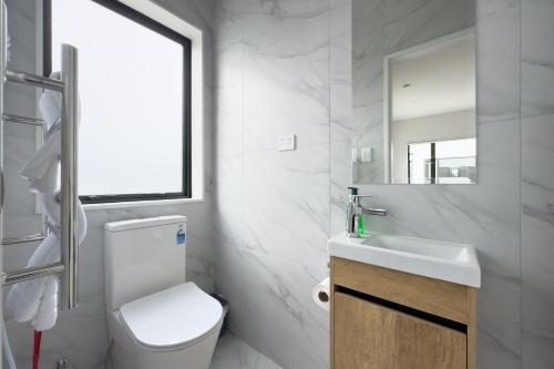 a bathroom with a toilet and a sink and a mirror at Cozy One-Bedroom Getaway in Takanini in Auckland