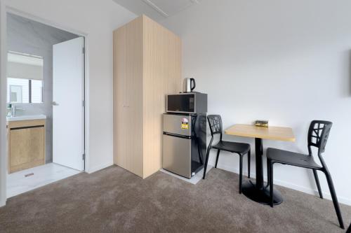 cocina con mesa, 2 sillas y microondas en Cozy One-Bedroom Getaway in Takanini, en Auckland