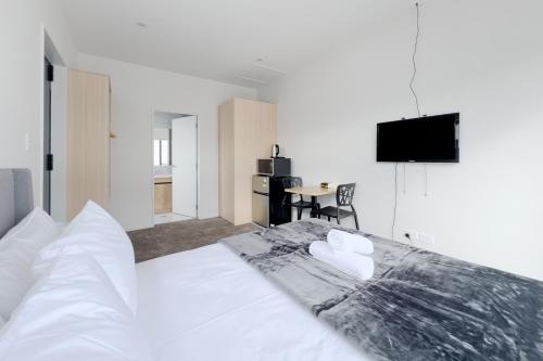 1 dormitorio con 1 cama blanca grande y toallas. en Cozy One-Bedroom Getaway in Takanini en Auckland