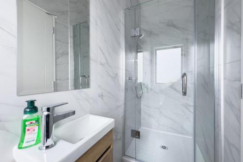 a white bathroom with a shower and a sink at Cozy One-Bedroom Getaway in Takanini in Auckland