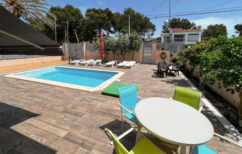 un patio con tavolo, sedie e piscina di Beautiful Home In Port Adriano With Kitchen a El Toro