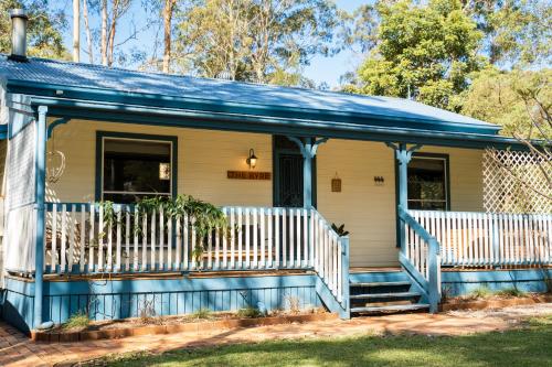 een klein huis met een blauwe en witte veranda bij Telegraph Retreat Cottages in Telegraph Point
