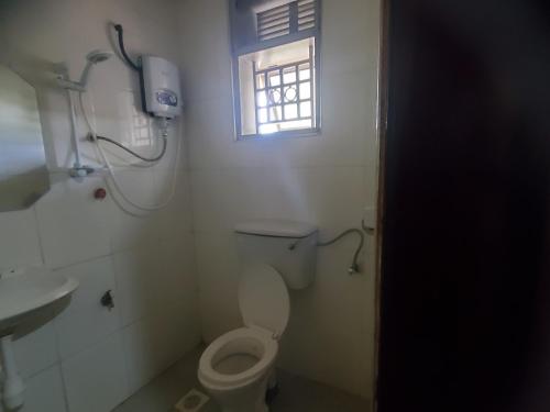 a bathroom with a toilet and a window at Bigodi Community Lodge in Kamwenge