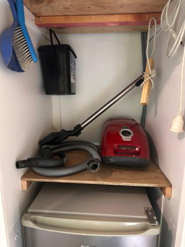 a vacuum cleaner sitting on a shelf next to a refrigerator at Rustic, Basic Cosy Alpine Hut, in the middle of the Mountains in Otira