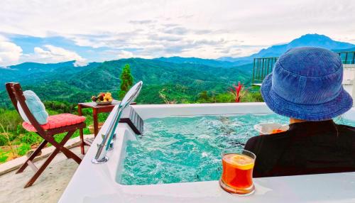a person sitting in a swimming pool with a drink at Hawun Valley Kiulu in Tamparuli