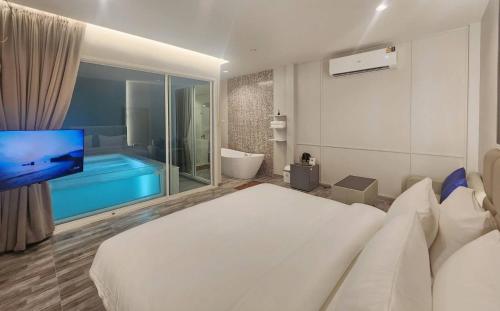 a bedroom with a large bed and a tub and a television at Skyline Resort in Ban Khlong Lat Bua Khao