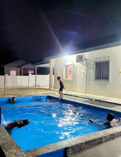 a group of people in a swimming pool at night at MyKampung Homestay in Rembau