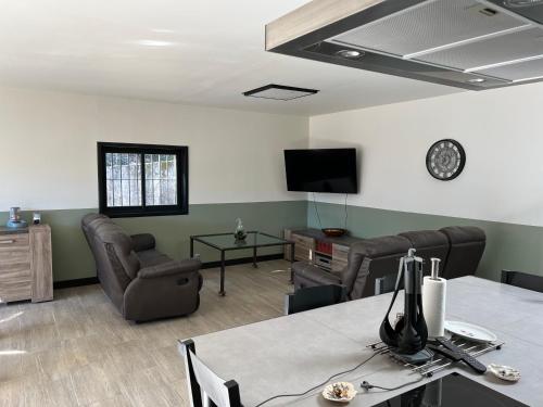 - un salon avec une table, des chaises et une télévision dans l'établissement Gîte chez marie, à Bessèges