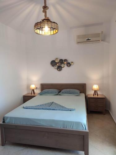 a bedroom with a bed with blue sheets and two lights at ANATOLI ROOMS SERIFOS in Serifos Chora