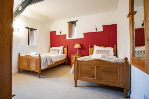 a bedroom with two beds and a red wall at Treworgie Barton - Duchy in Bude