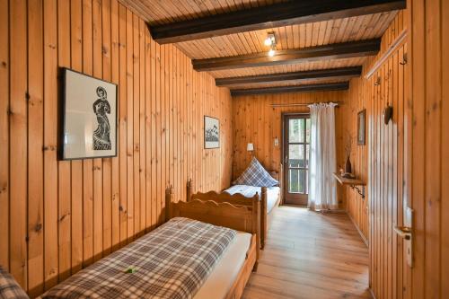 een slaapkamer met 2 bedden in een kamer met houten wanden bij Naturidyll Kollnbergmühle in Fürstenstein