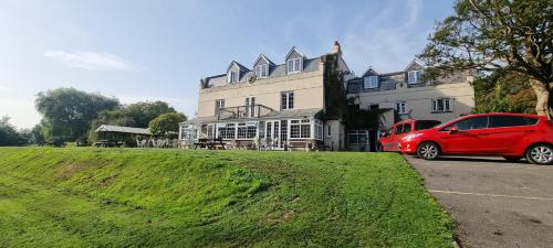 a red car parked in front of a large house at Trelawney Cottage, Sleeps up to 4, Wifi, Fully equipped in Menheniot