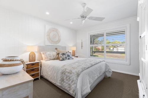 a white bedroom with a bed and a window at The Bridge Walk in Manyana