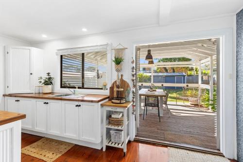 a kitchen with white cabinets and a table and a patio at The Bridge Walk in Manyana