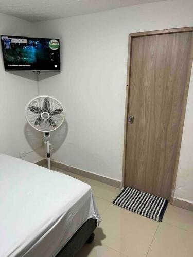 a room with a bed and a door and a fan at Apto de lujo 101, 2 hab 3 baños in Cali