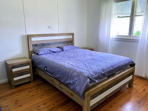 Schlafzimmer mit einem Bett mit blauer Decke in der Unterkunft The Butterfly House in Bendalong in Manyana